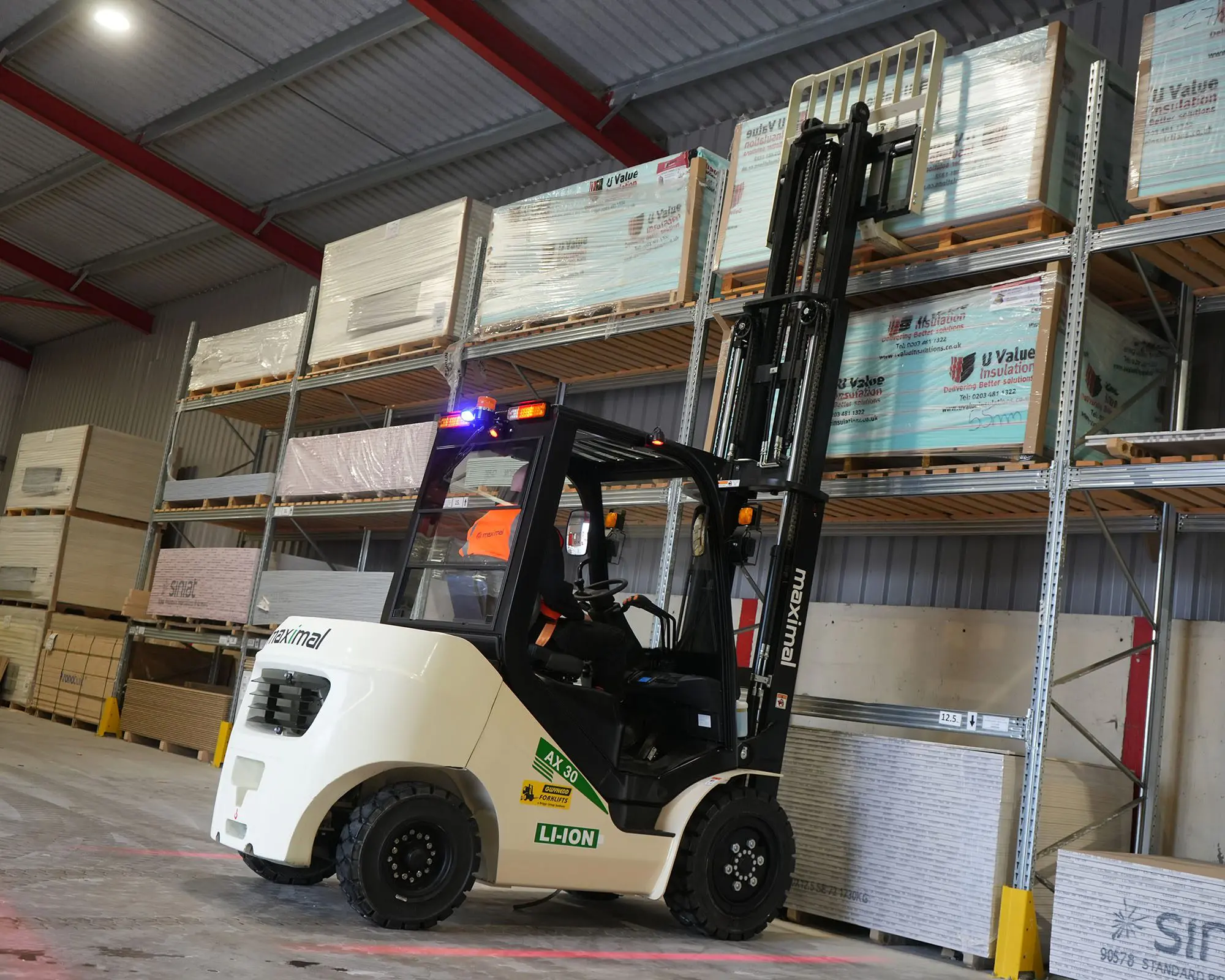 A forklift lifting a pallet of goods in a warehouse with shelving in the background.
