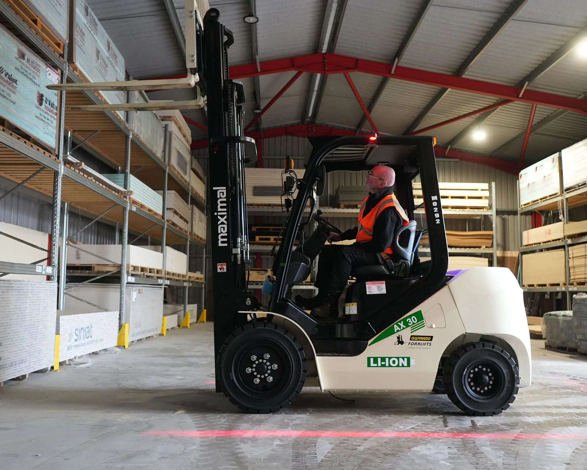 A forklift maneuvering through shelves in a warehouse, accompanied by stacks of materials.