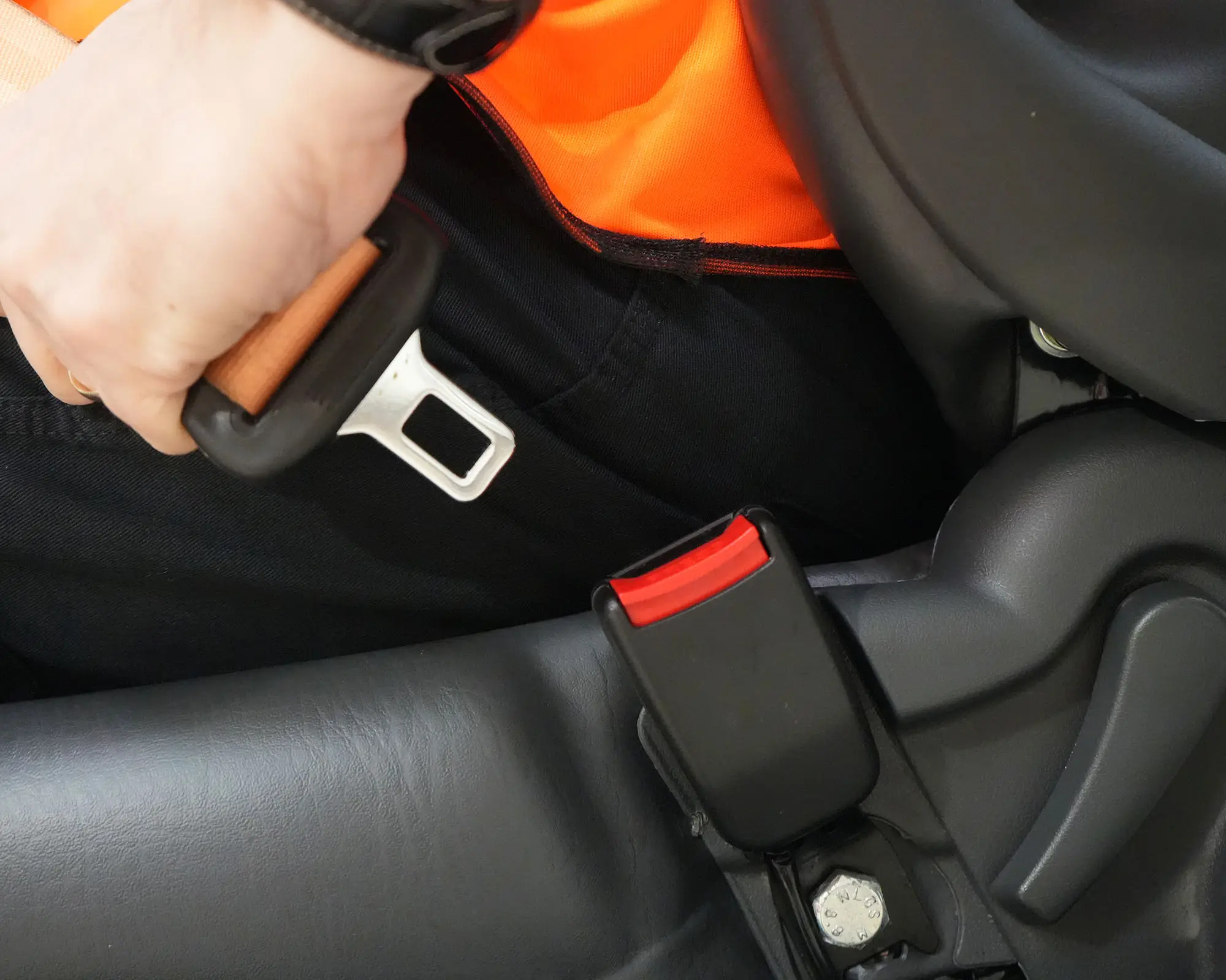 Close-up of a person's hand fastening a seatbelt in a vehicle