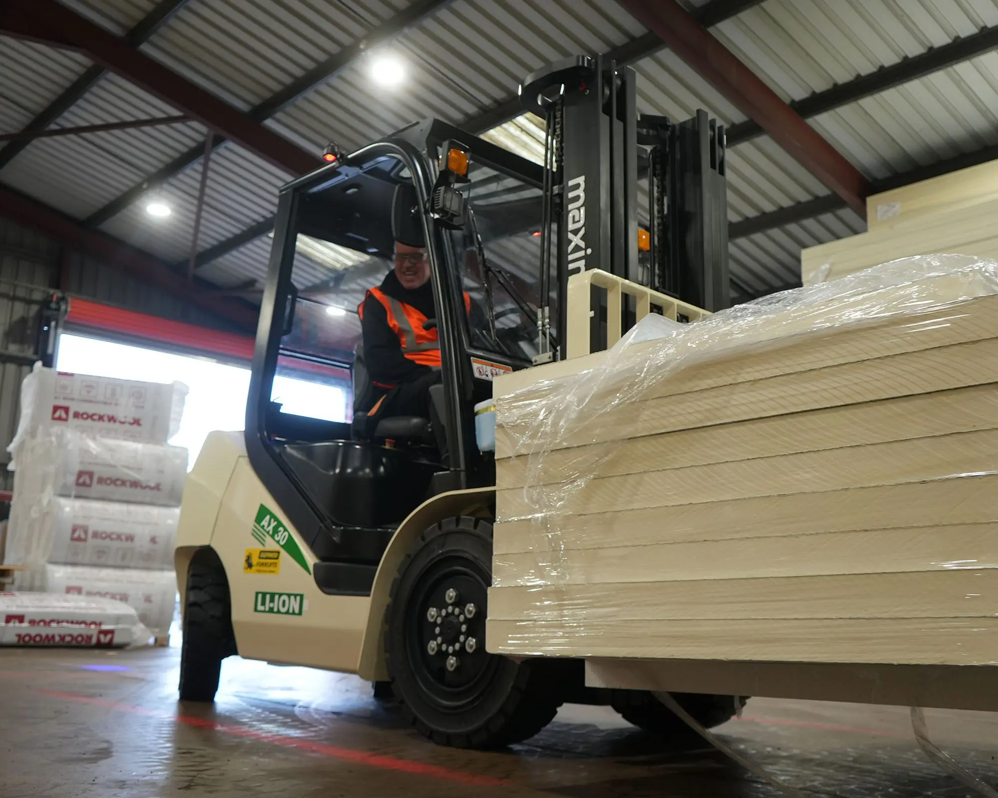 A forklift operating in a warehouse, lifting a load of stacked materials.