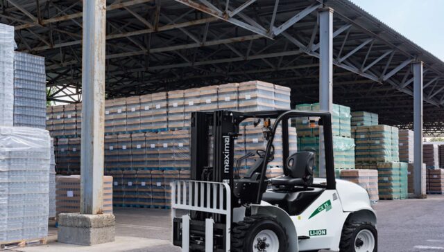 A white forklift with a black frame parked in a warehouse surrounded by stacks of materials.
