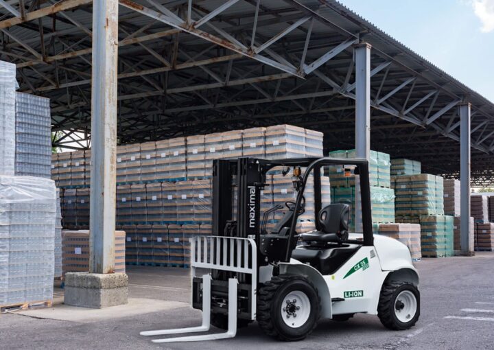 A white forklift with a black frame parked in a warehouse surrounded by stacks of materials.
