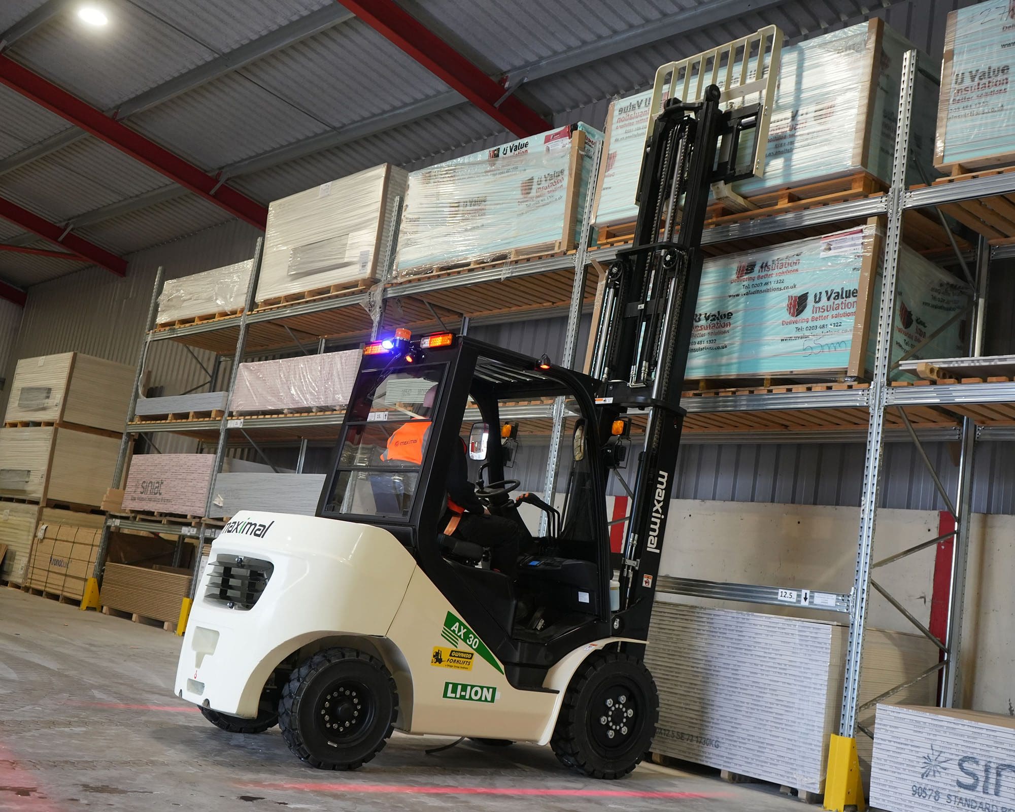 A forklift lifting a pallet of goods in a warehouse with shelving in the background.