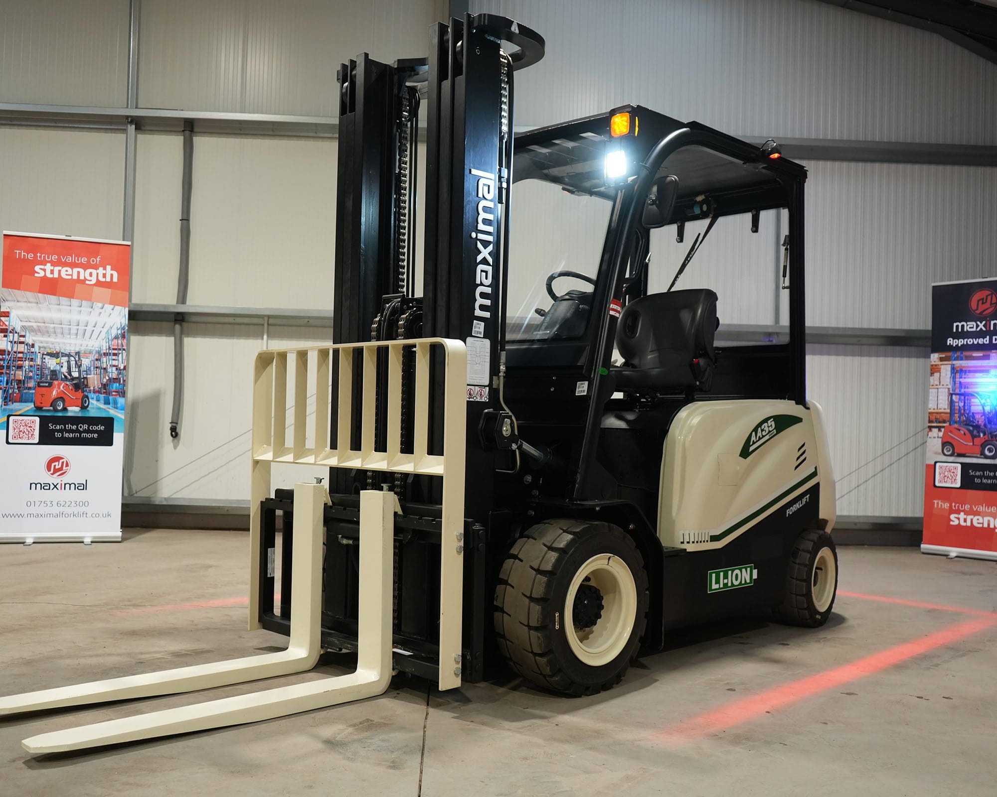 Maximal Forklift in Warehouse Setting A Maximal forklift with extended forks parked indoors in a warehouse environment.