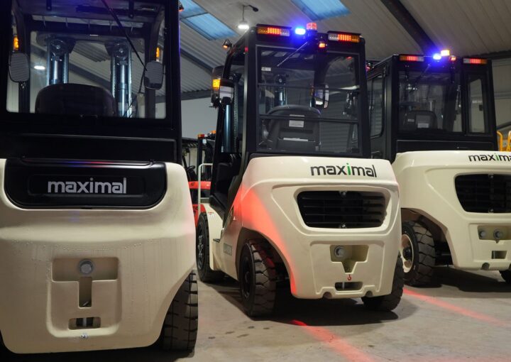 Three Maximal branded forklifts parked in a warehouse with lights on.