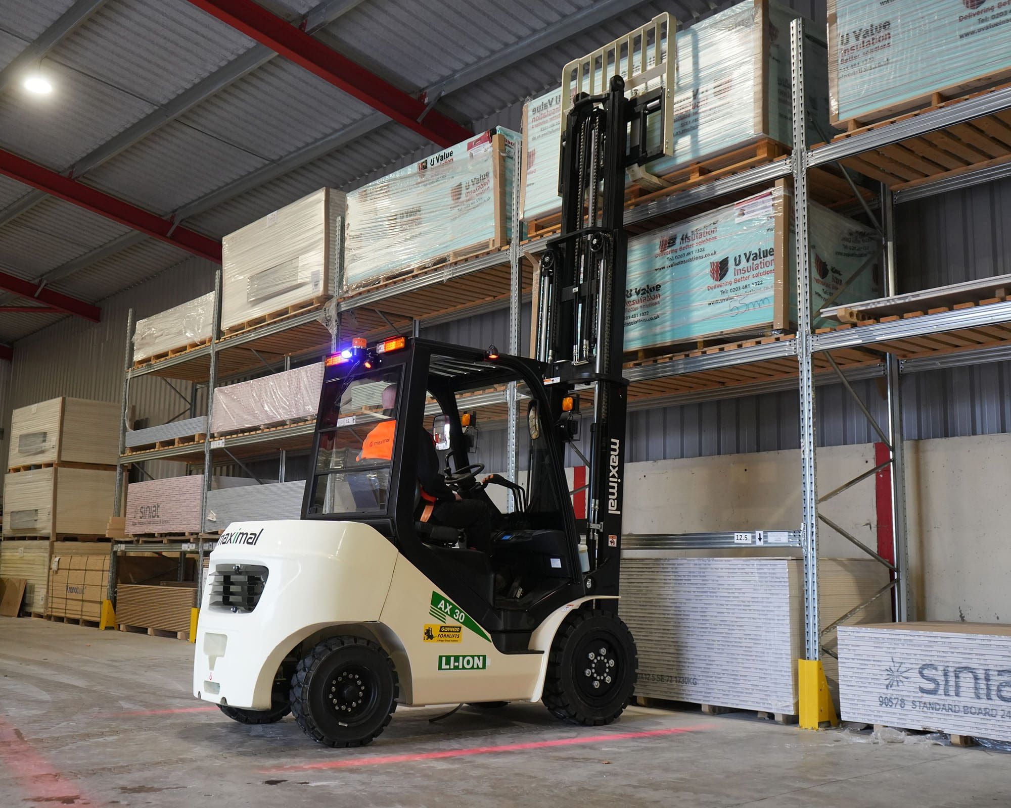 A forklift in a warehouse lifting cargo from a high shelf, showcasing industrial equipment and organized storage.
